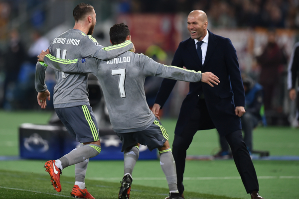 Real Madrid's Portuguese forward Cristiano Ronaldo (C) celebrates with Real Madrid's defender Sergio Ramos and Real Madrid's French coach Zinedine Zidane after scoring during the UEFA Champions League football match AS Roma vs Real Madrid on Frebruary 17, 2016 at the Olympic stadium in Rome.     AFP PHOTO / ALBERTO PIZZOLI / AFP / ALBERTO PIZZOLI